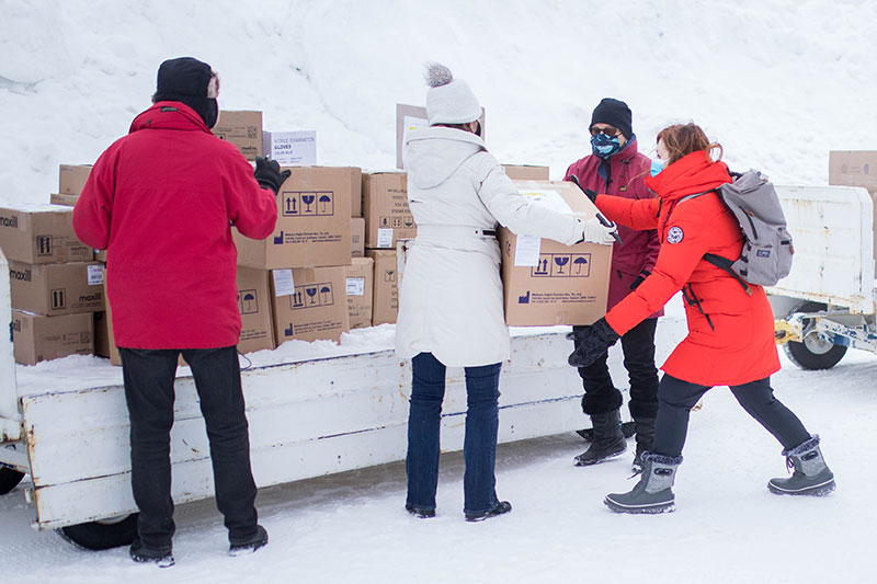 4 people transferring boxes from one person to another