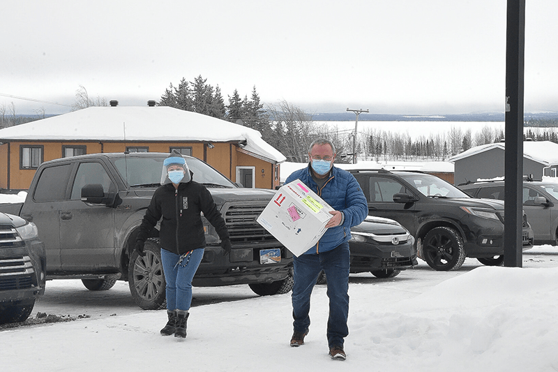 Man and woman bringing box into Oujé-Bougoumou clinic