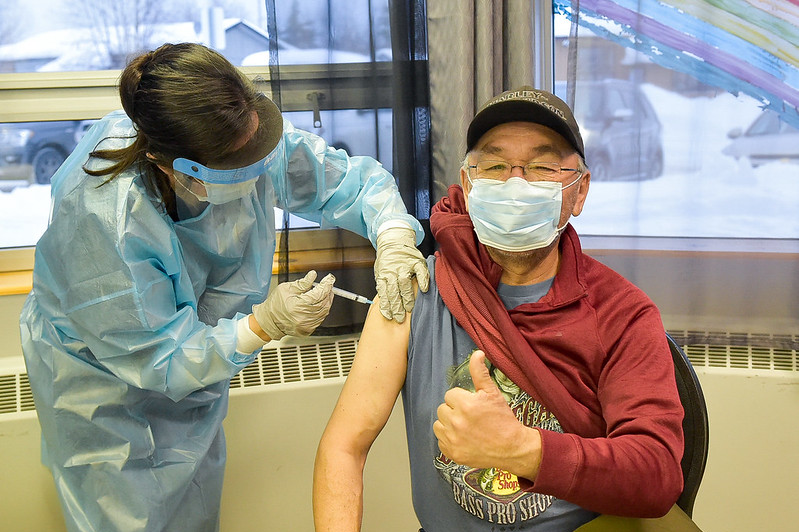 Elder gives thumbs up while receiving vaccine
