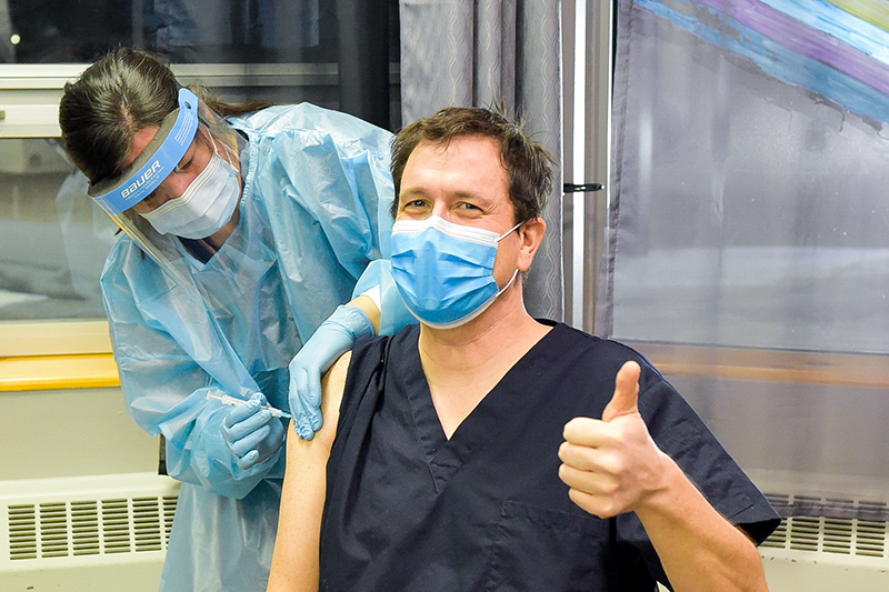 Frontline worker gives thumbs up while being vaccinated