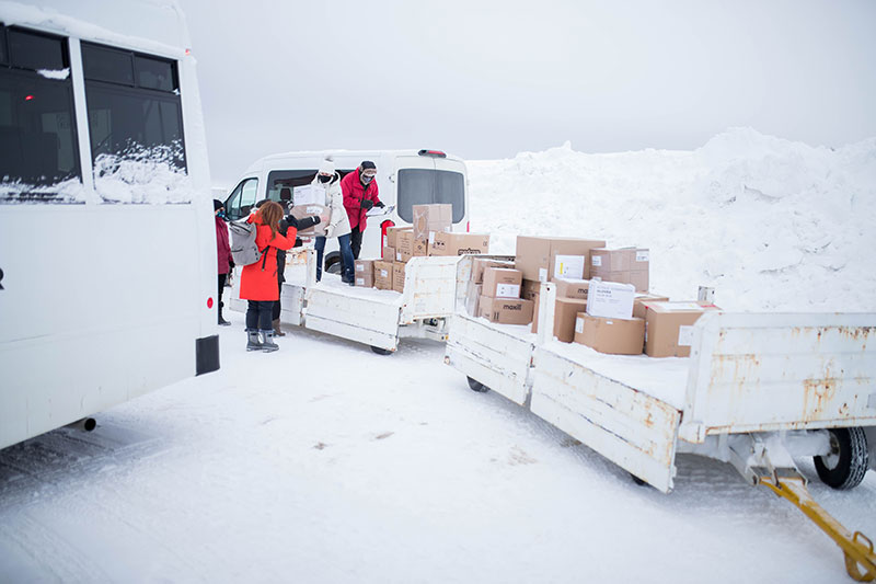 People carrying boxes onto vehicle