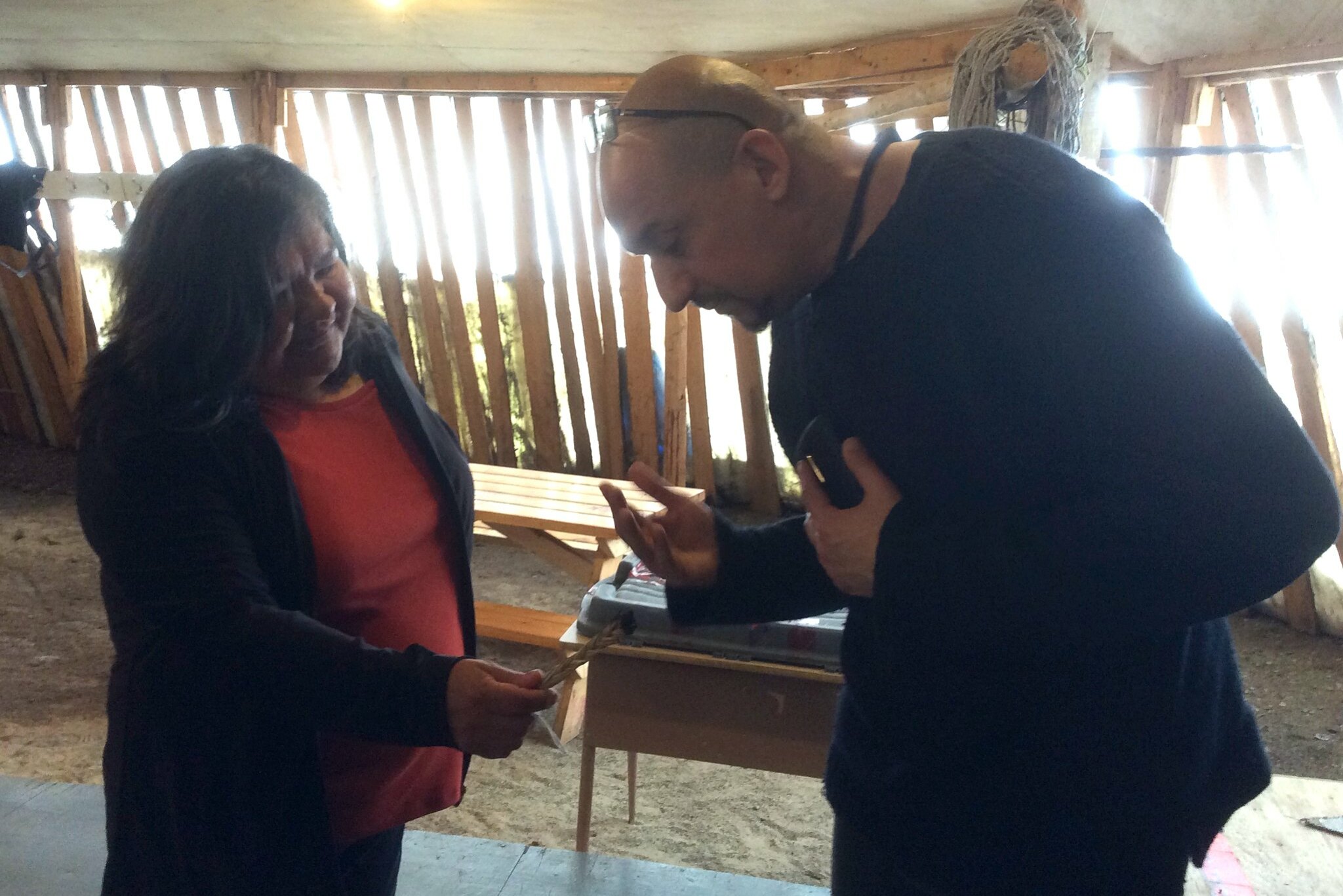 A woman offers a man a smudge of sweetgrass