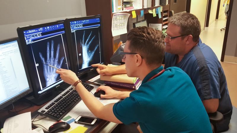 2 men looking at x-ray of hand on screen