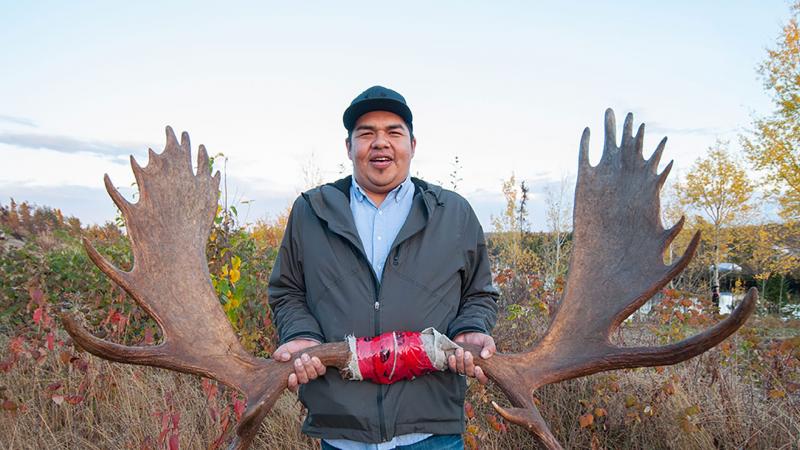 Smiling man showing off moose antlers