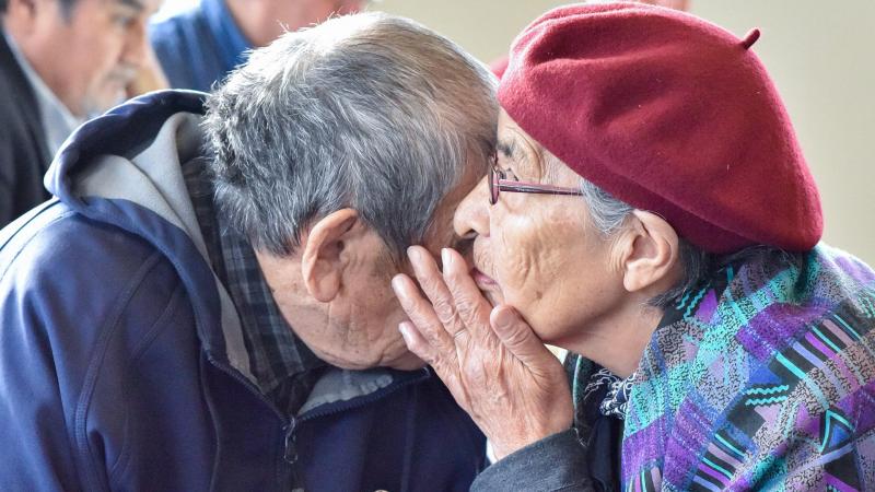 Elder whispering into another elder's ear