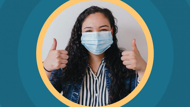 Woman wearing mask and giving two thumbs-up