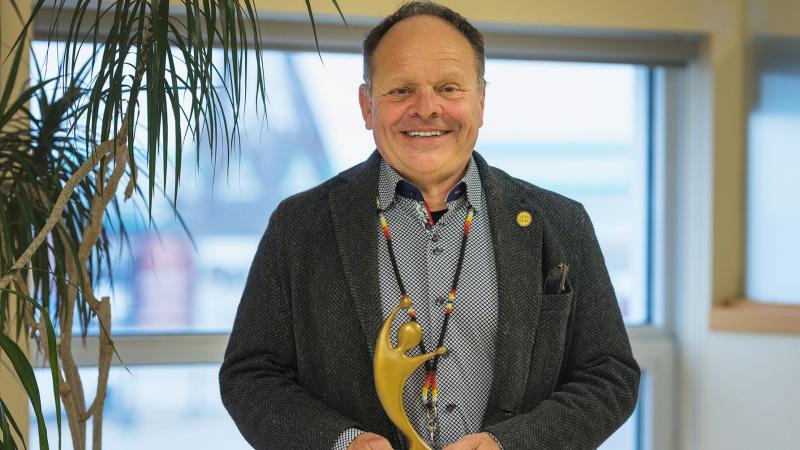 Executive Director Daniel St-Amour smiles while holding Raymond Carignan Award for Excellence