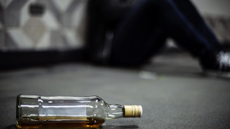 Bottle of alcohol on the ground with person in background