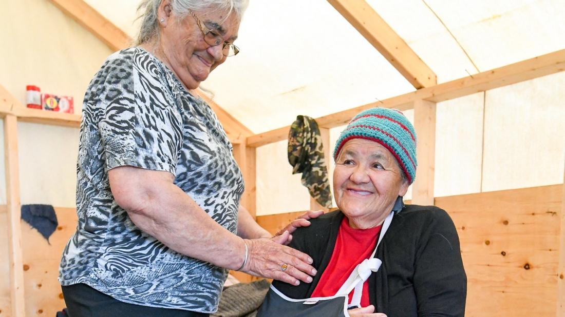 Woman helping a smiling elder with arm in sling