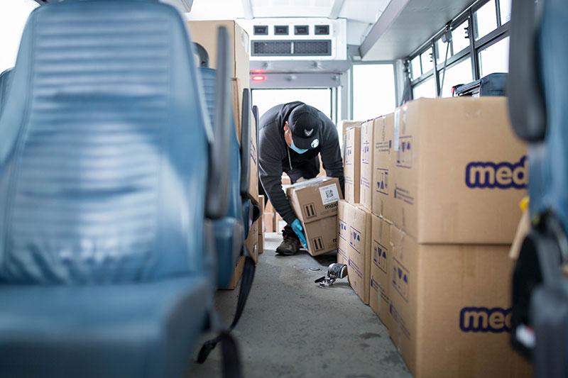 Man picks up boxes from bus floor