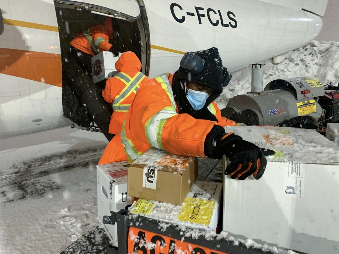 Ramp workers load boxes onto plane