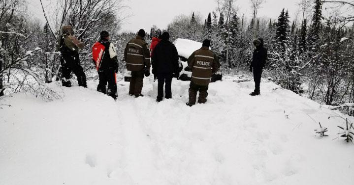 Search and rescue team standing next to vehicle stuck in the snow