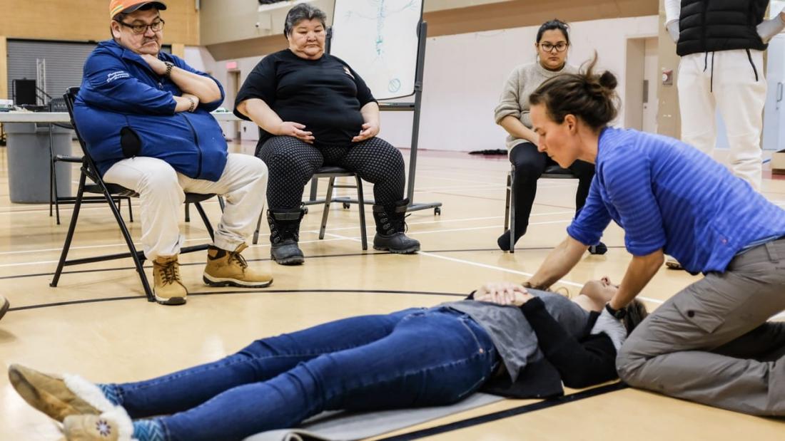 Woman shows first aid technique to group of people