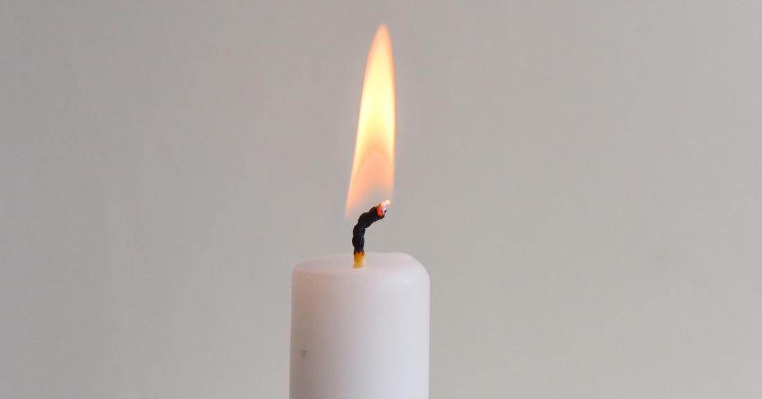 Burning candle with a grey background