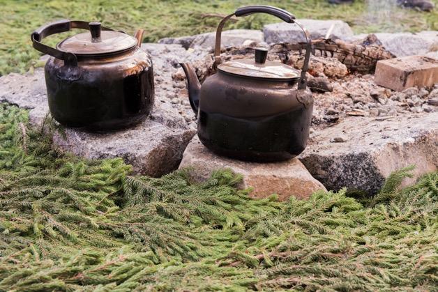 2 kettles sit on rocks inside teepee