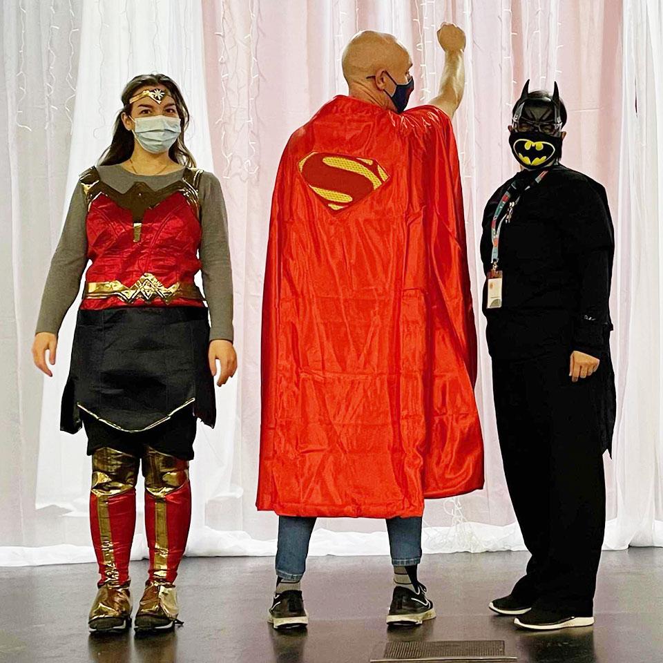 3 people dressed up as superheroes - Wonder Woman, Super Man, and Bat Man.