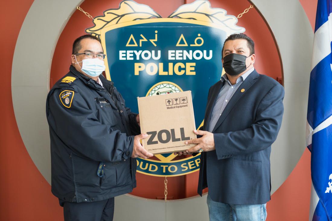 Chairperson holds box of defibrillators with Eeyou Eenou Police Officer