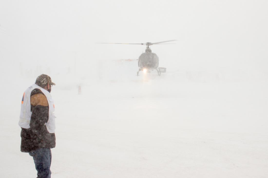 Man stands in the snow as helicopter lands