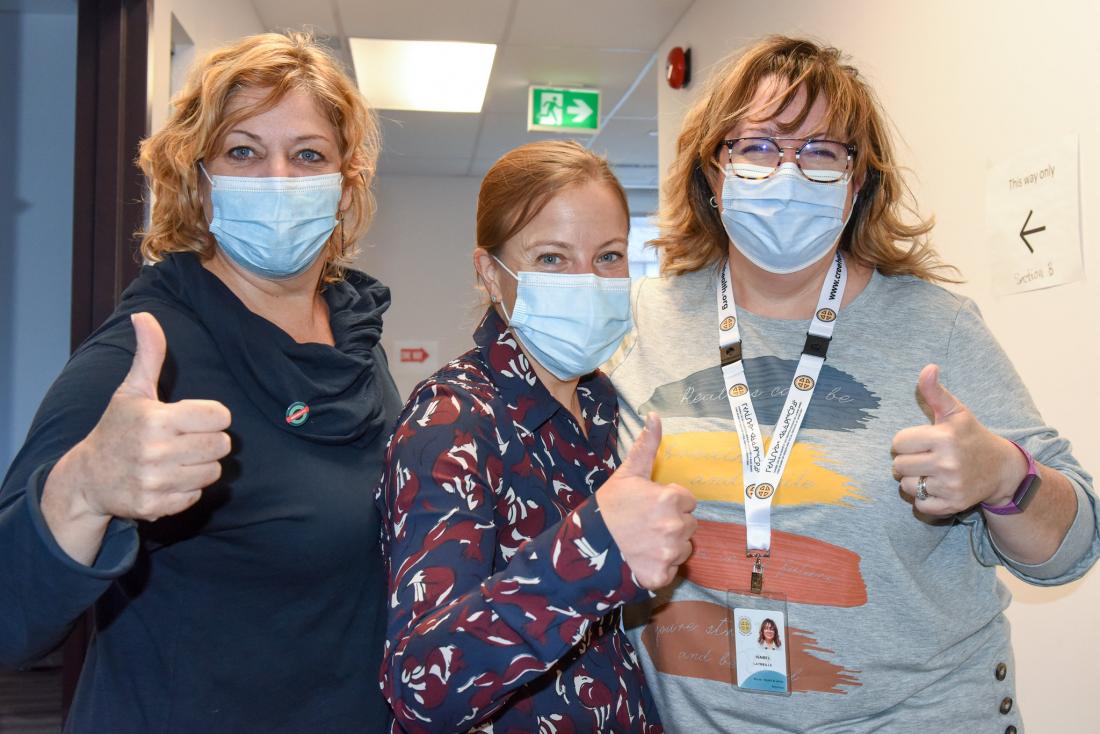 Three health professionals pose with their thumbs up