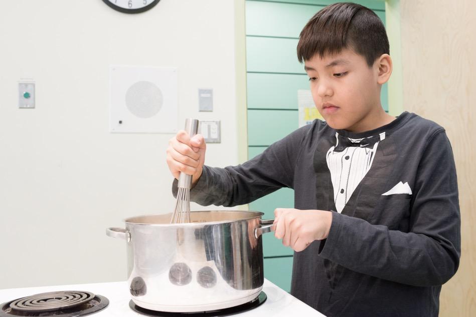 Child stirring contents of a pot on a stove
