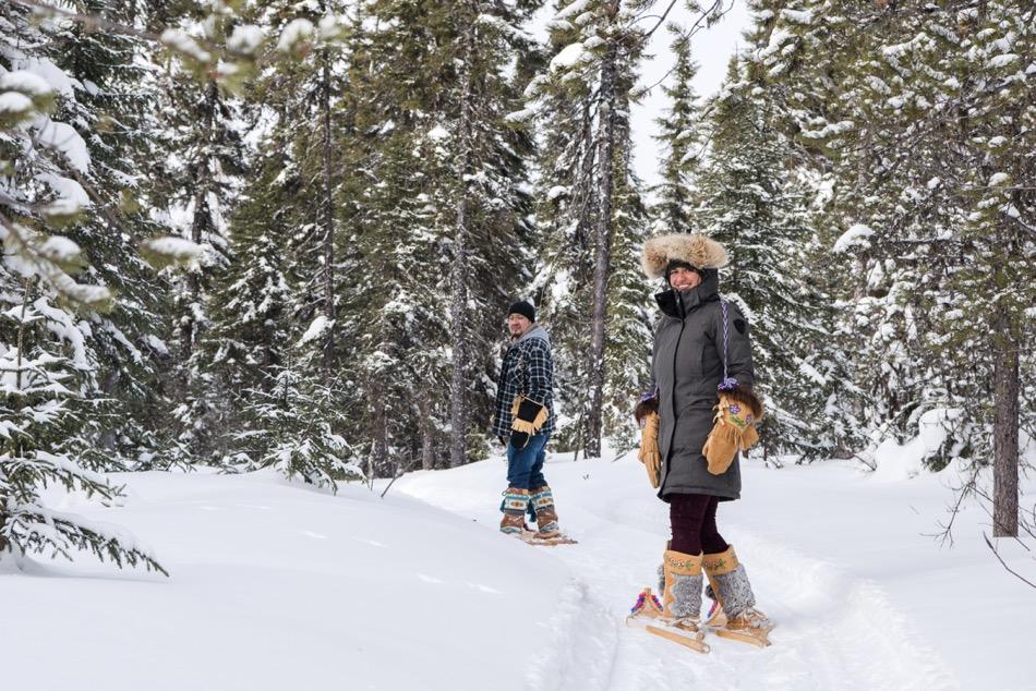 Man and woman on snowshoes walk into forest