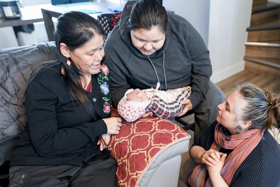 3 woman gaze at a newborn baby
