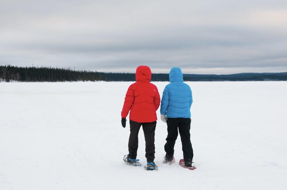 2 people walking on snowshoes on lake