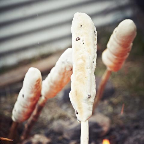 Bannock on a stick cooking over fire