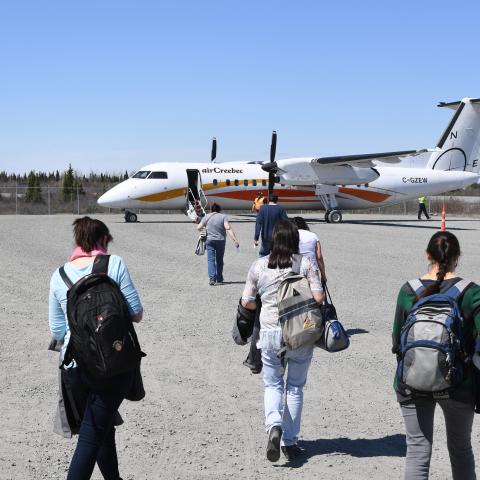 Women walking towards Air Creebec plane with carry-on luggage
