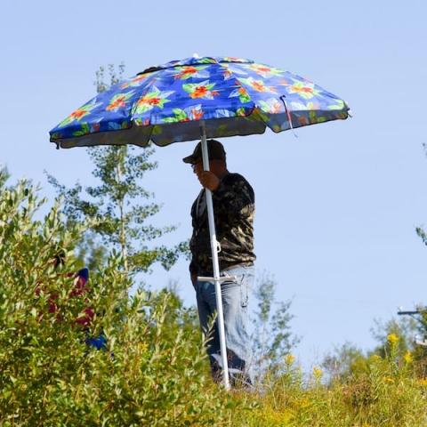 Man standing under sun umbrella in the bush