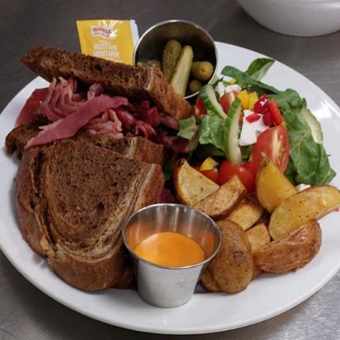Smoked meat sandwich, salad and potatoes on a plate